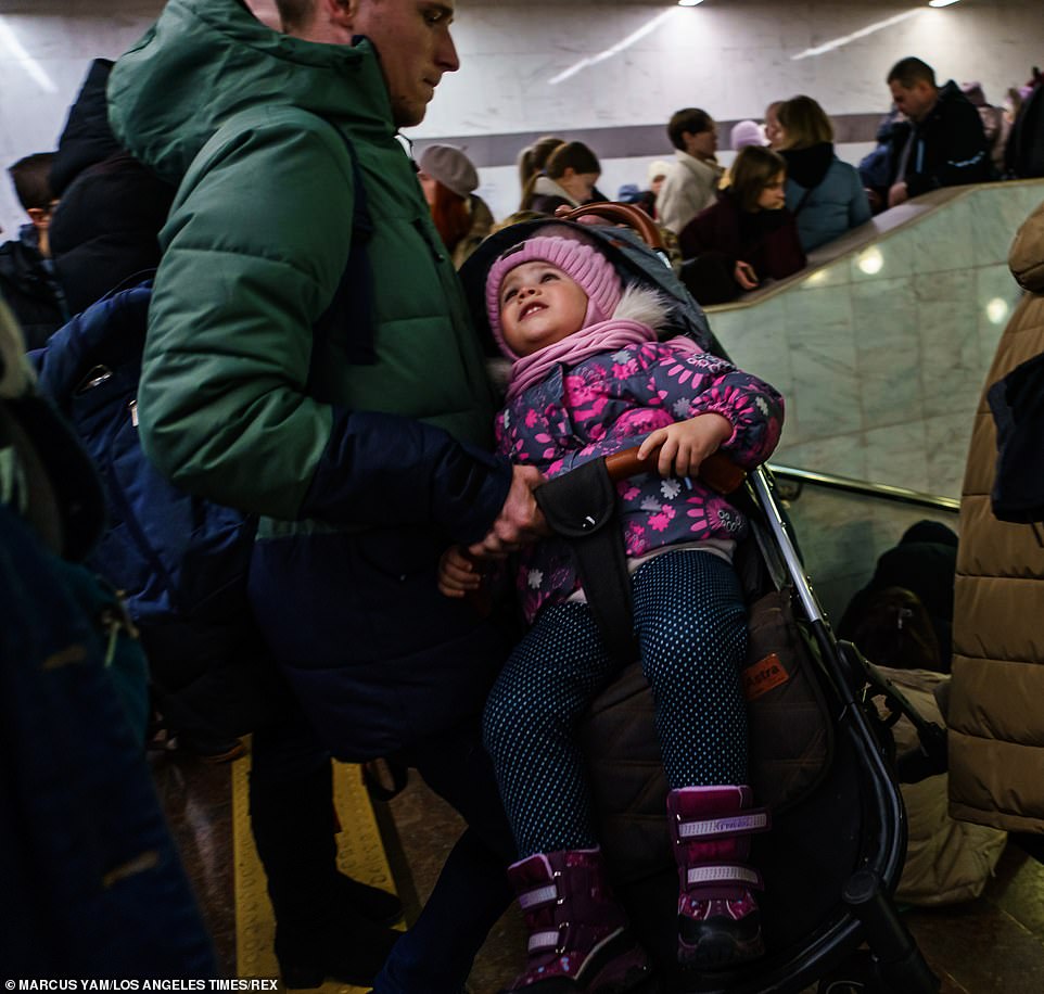 Terrified Ukrainians, including families with young children and pets, filled Kharkiv's subway station on Thursday. Above, a father carried his anxious-looking baby in a stroller down the steps into the station