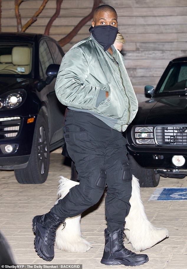 Dad look: Kanye wore an army green down jacket, black cargo pants and boots.  There were pads on his pants above the knees.