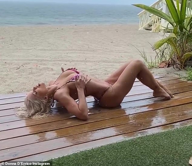 Sizzling: The 54-year-old Baywatch vet lay sprawled on a wooden plank on the beach as water rained down on her toned body
