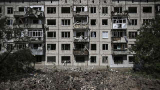 A picture shows a crater in front of a damaged apartment building after a rocket attack in the town of Soledar in eastern Ukraine's Donbass region June 4, 2022. - Russian artillery hits Ukraine's eastern Donbass region with fierce fighting for the town of Severodonetsk, but the local Governor says there has been some progress in pushing back invading forces.  (Photo by ARIS MESSINIS / AFP)
