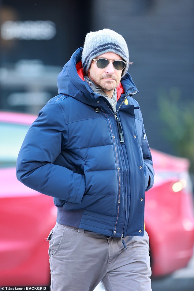 Staying warm: He completed his outfit with a gray beanie, trainers and black aviator sunglasses