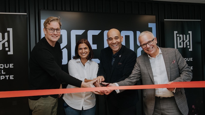 Four people smile and cut the ribbon for the official inauguration of the Beenox studio in Montreal. 