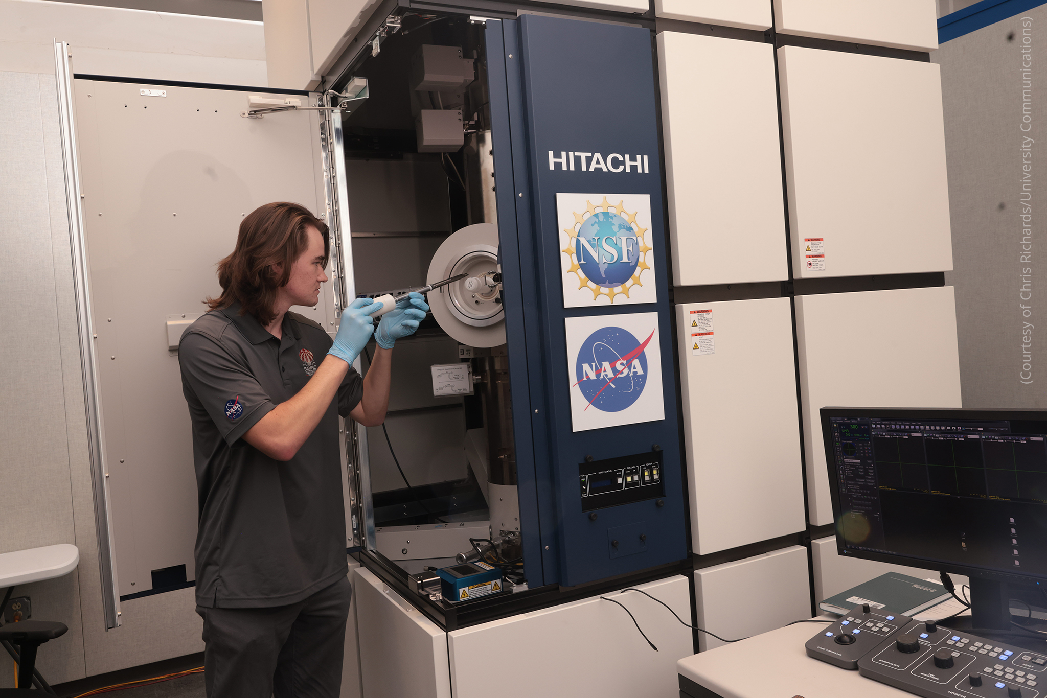 Lucas Smith places a sample in a machine (Courtesy of Chris Richards/University Communications)